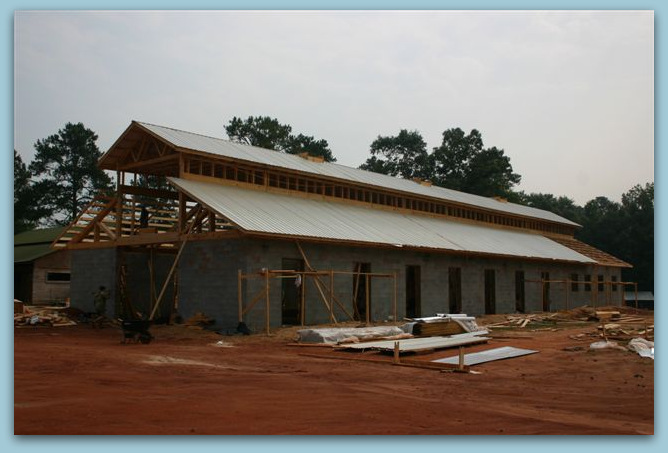 Adding The Metal Roof - Photo Image View Of Twelve Stall Monitor Style Horse Barn Built With Concrete Blocks and Stucco Finish